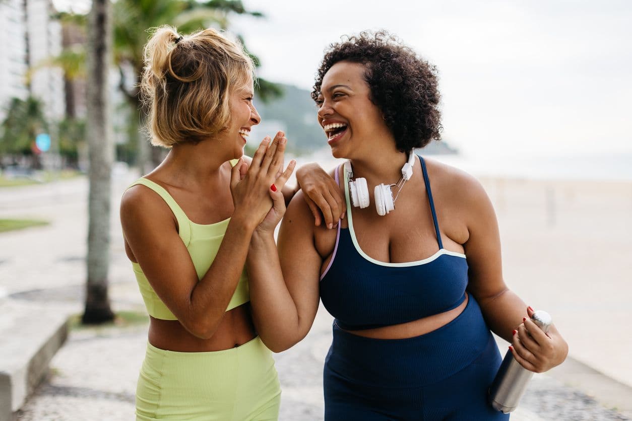 Two women in workout sets smiling and giving each other a high five